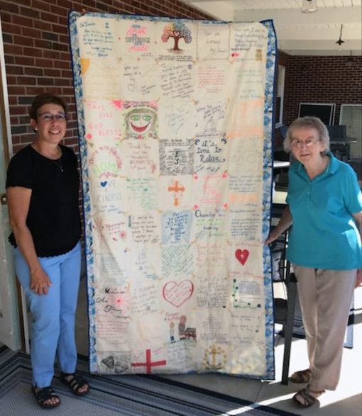 Sr Imelda receives the keeping quilt offered by St Philomena school community